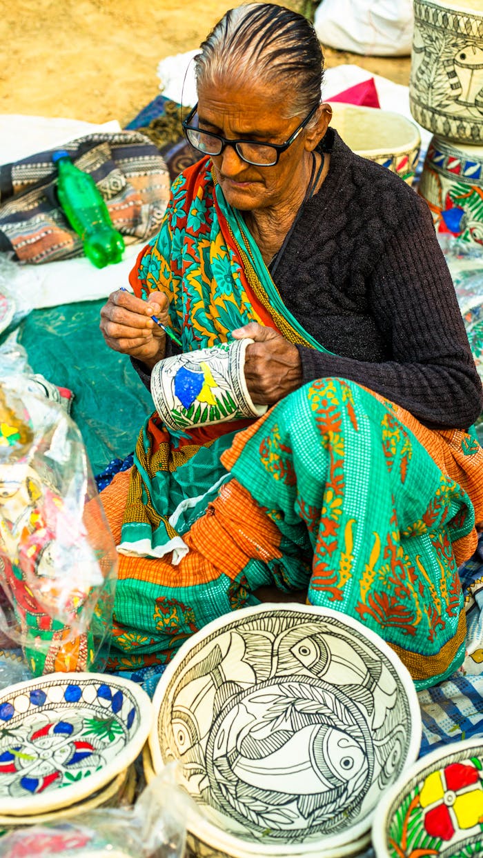 An elderly woman skillfully creating traditional handicrafts at a local Indian market.